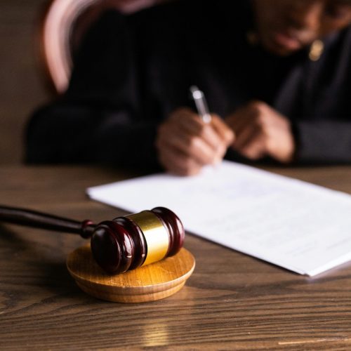 Judge signing documents at desk with focus on gavel, representing law and justice.