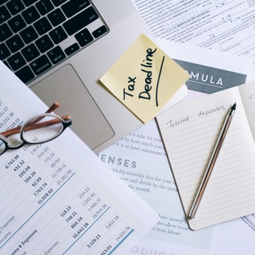 Workspace with laptop, documents, and tax deadline note for financial management.